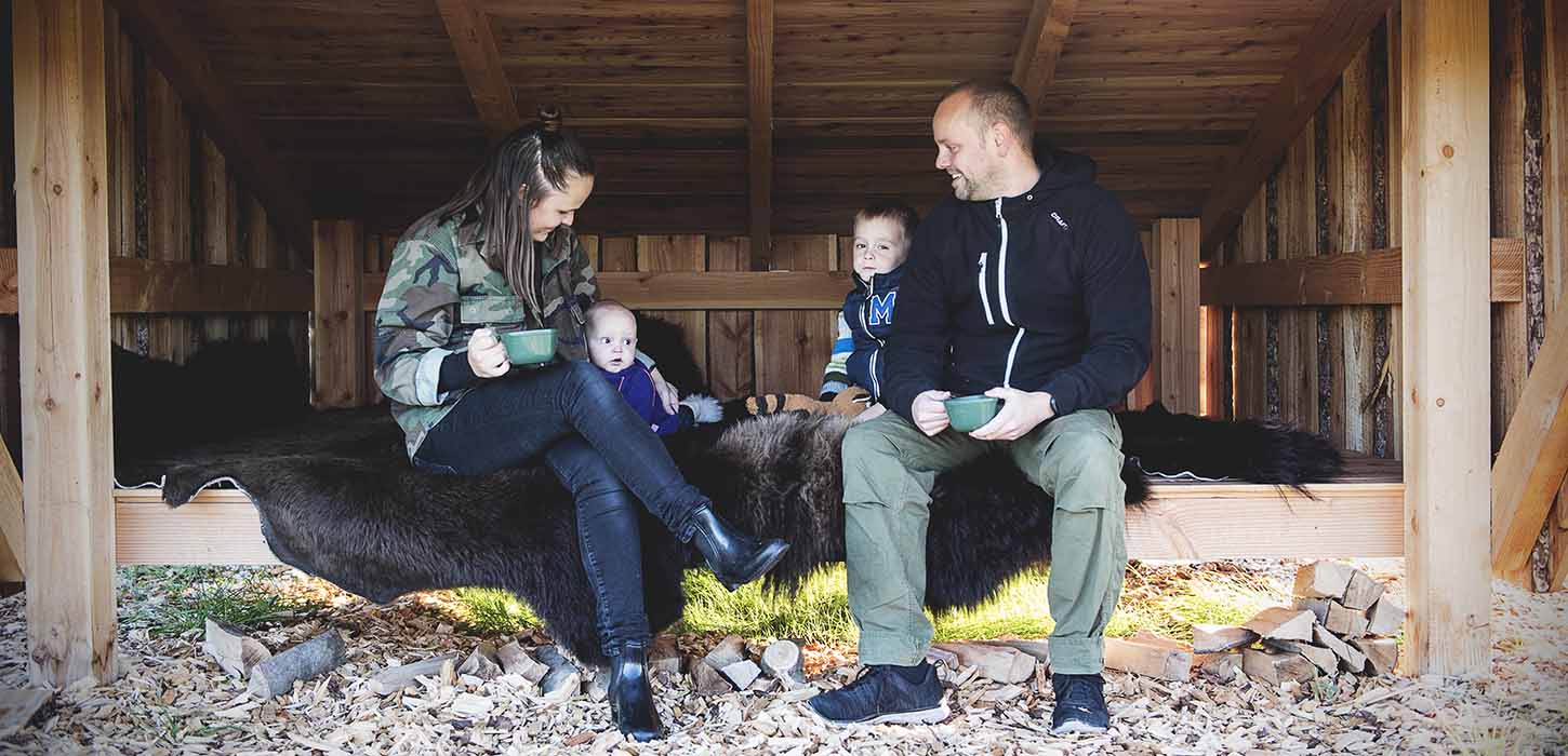 Mor, far og to små børn slapper af på et bisonskind i et stort shelter