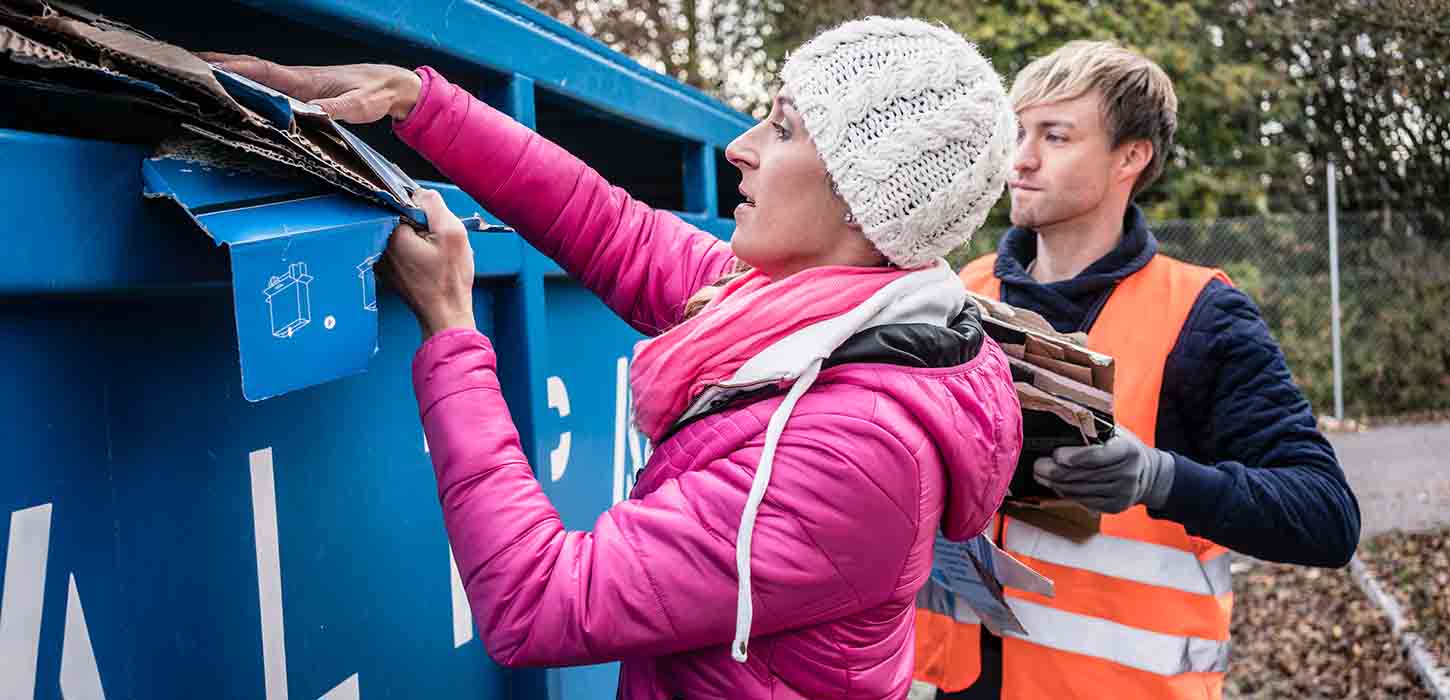 Eine Frau legt Karton in den Kartonbehälter