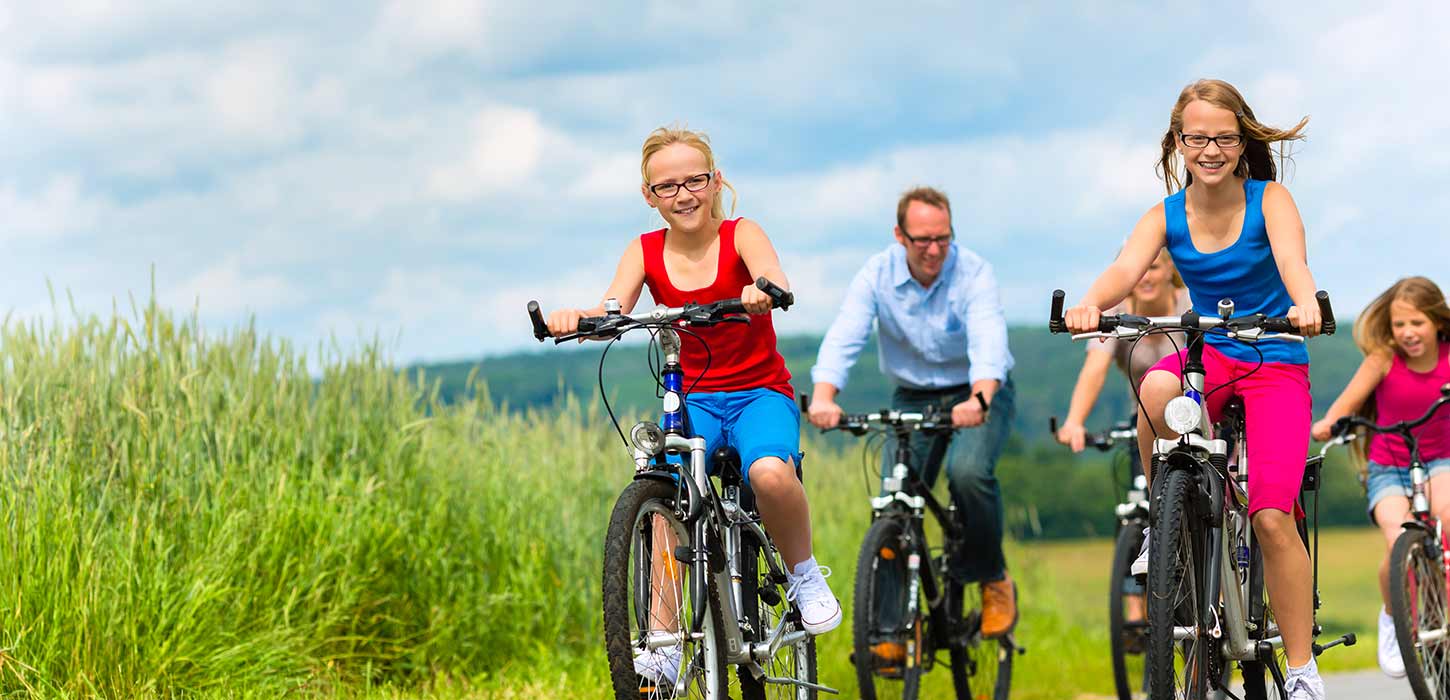 Piger cykler forrest på cykeltur med familien