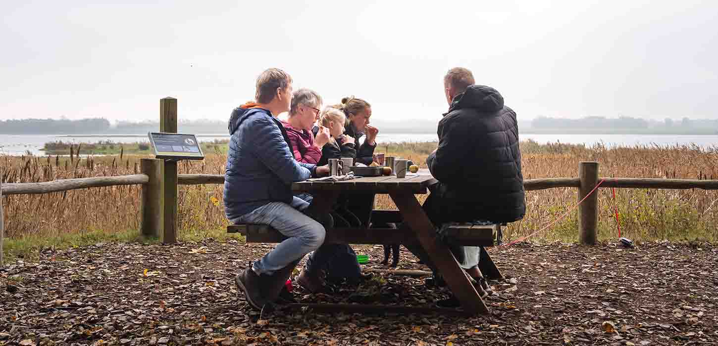 Familie holder picnic på Gyldensteen Strand i efteråret