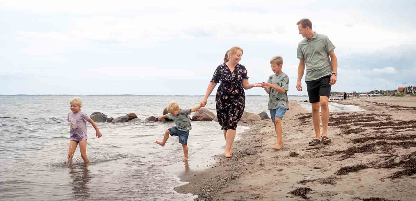Familie går tur på stranden ved Hasmark