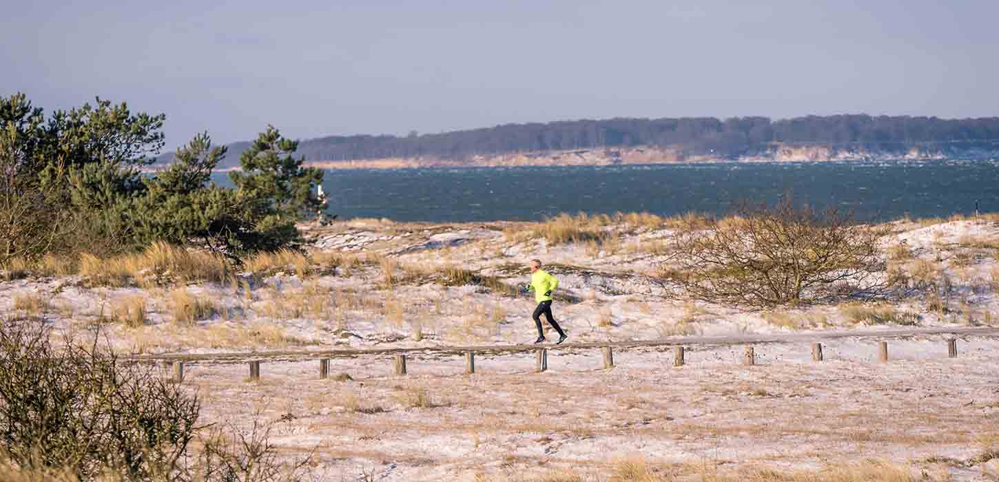 Løber i vintertid på Flyvesandeet dækket af sne og med udsigt til havet