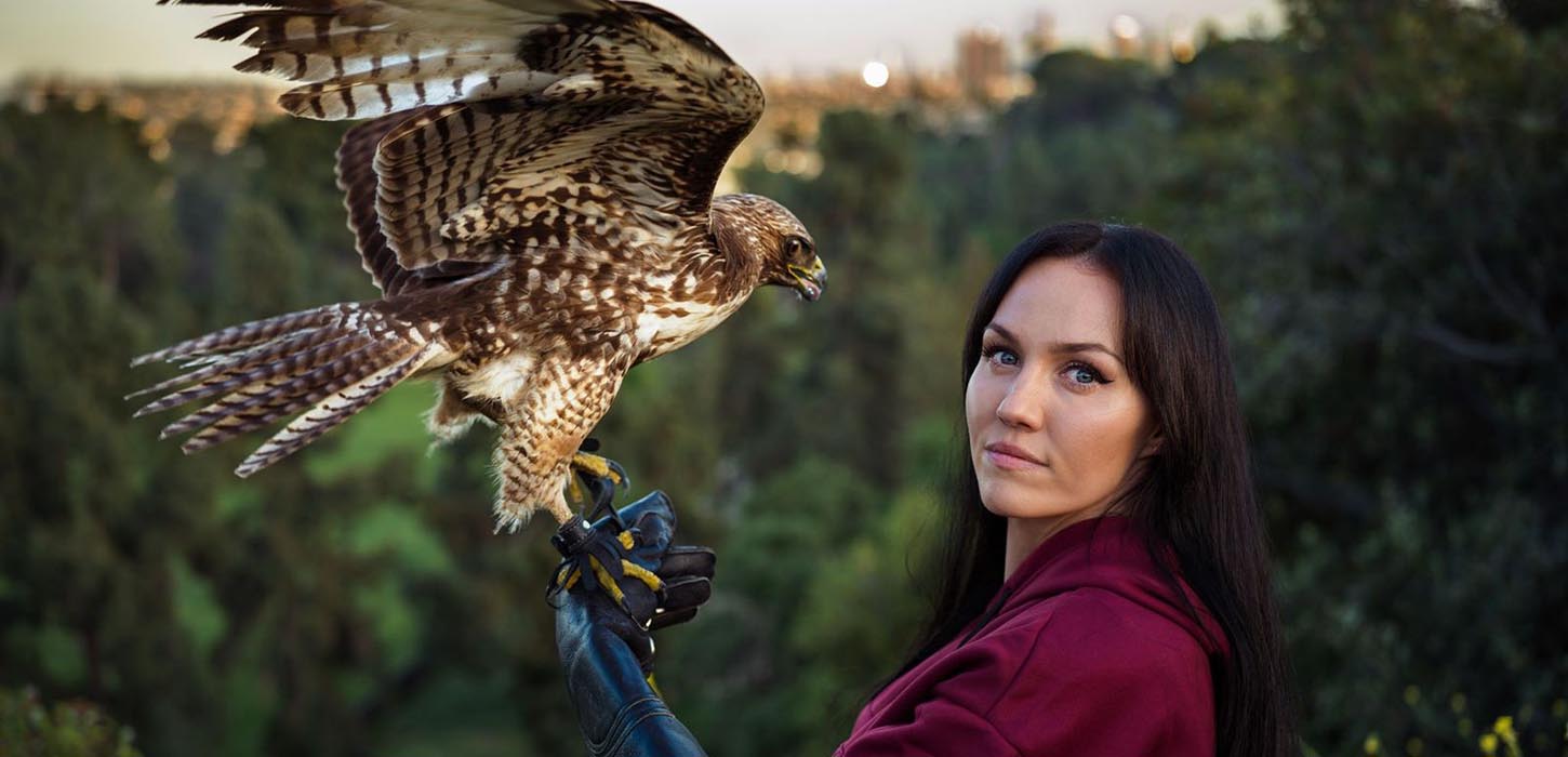 Kvindelig falkoner foran skovområde af fotograf Mihaela Noroc