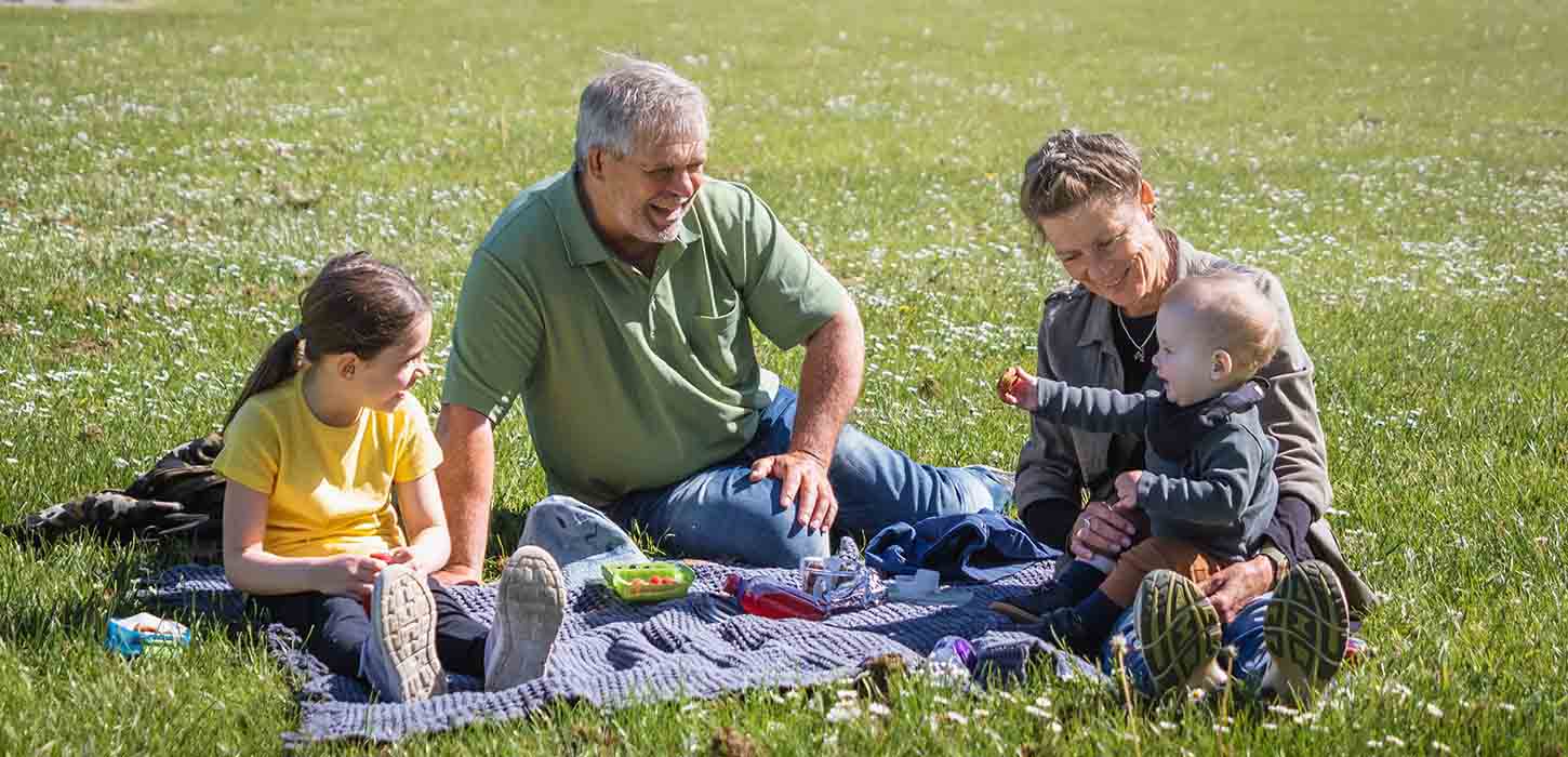 Bedsteforældre holder picnic med børnebørn på græsset ved Fuglsang